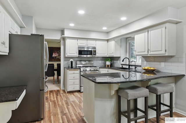 1725 N 162nd St, Omaha, NE 68118 - kitchen featuring stainless steel appliances, a peninsula, a sink, light wood-style flooring, and backsplash