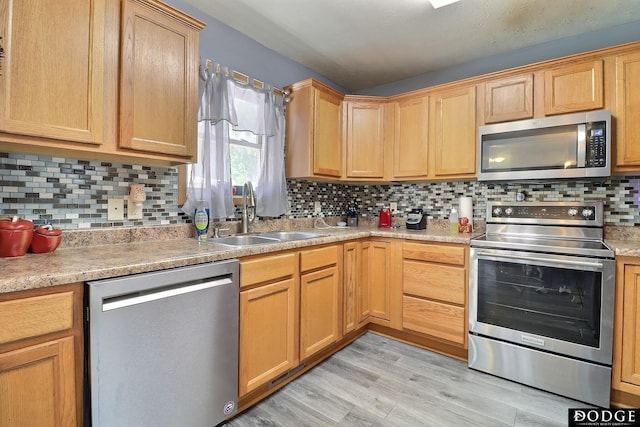 950 E 16th St, Fremont, NE 68025 - kitchen featuring appliances with stainless steel finishes, a sink, backsplash, light wood-style floors, and light countertops