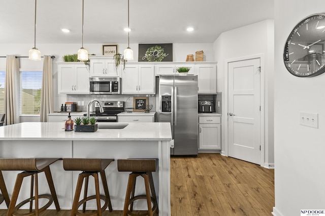 7717 N 108th St, Omaha, NE 68142 - kitchen featuring appliances with stainless steel finishes, a breakfast bar, backsplash, white cabinetry, and recessed lighting