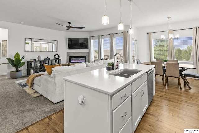 7717 N 108th St, Omaha, NE 68142 - kitchen featuring a sink, a ceiling fan, a glass covered fireplace, dishwasher, and a kitchen island with sink