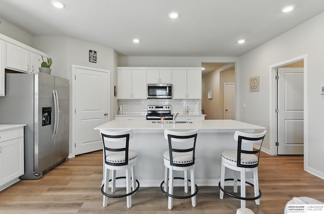 6312 Centennial Rd, Papillion, NE 68157 - kitchen with appliances with stainless steel finishes, a sink, a breakfast bar area, white cabinetry, and tasteful backsplash