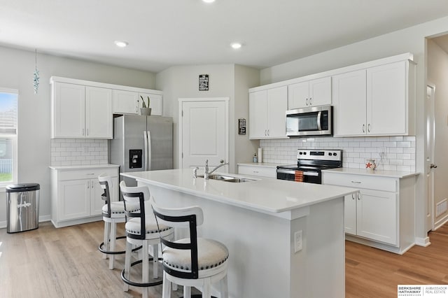 6312 Centennial Rd, Papillion, NE 68157 - kitchen featuring appliances with stainless steel finishes, a sink, light wood-style floors, a kitchen breakfast bar, and recessed lighting
