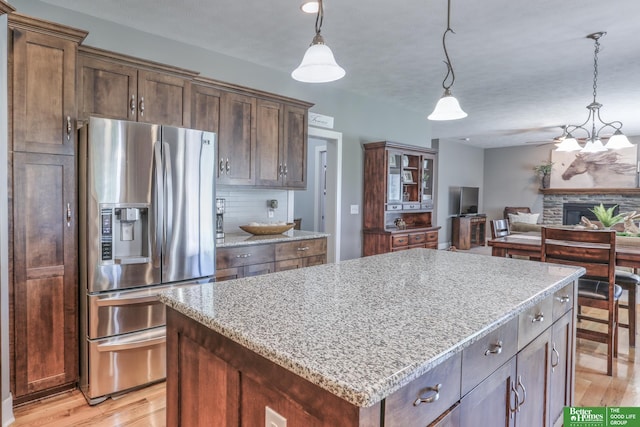 10311 S 124th St, Papillion, NE 68046 - kitchen with stainless steel refrigerator with ice dispenser, light wood-style floors, a center island, and light stone counters