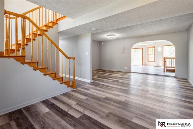 1511 Lorraine Ave, Bellevue, NE 68005 - unfurnished living room featuring arched walkways, wood finished floors, baseboards, stairs, and a textured ceiling