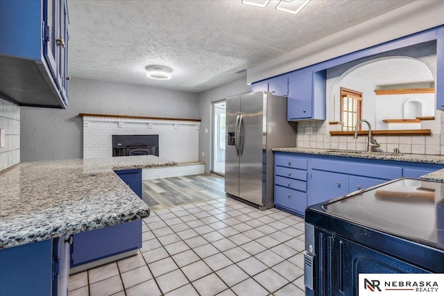 1511 Lorraine Ave, Bellevue, NE 68005 - kitchen with blue cabinetry, a sink, stainless steel refrigerator with ice dispenser, a textured ceiling, and electric range oven