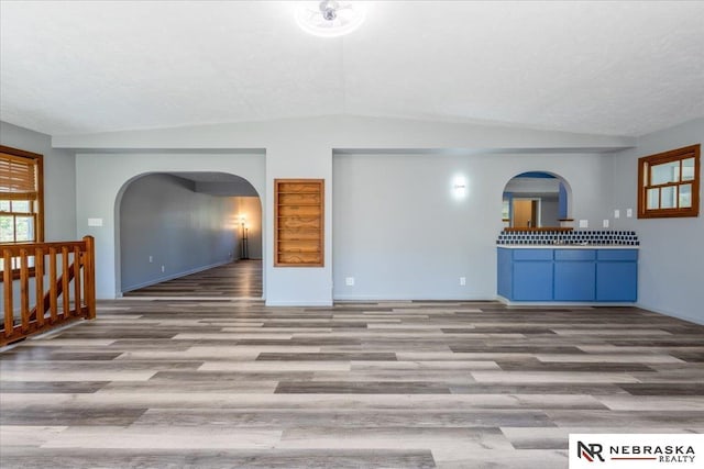 1511 Lorraine Ave, Bellevue, NE 68005 - unfurnished living room with arched walkways, wood finished floors, lofted ceiling, and baseboards