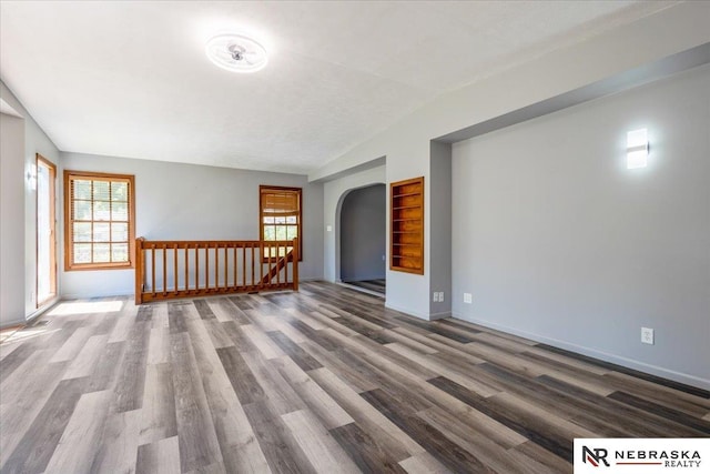 1511 Lorraine Ave, Bellevue, NE 68005 - empty room featuring wood finished floors, arched walkways, healthy amount of natural light, baseboards, and vaulted ceiling