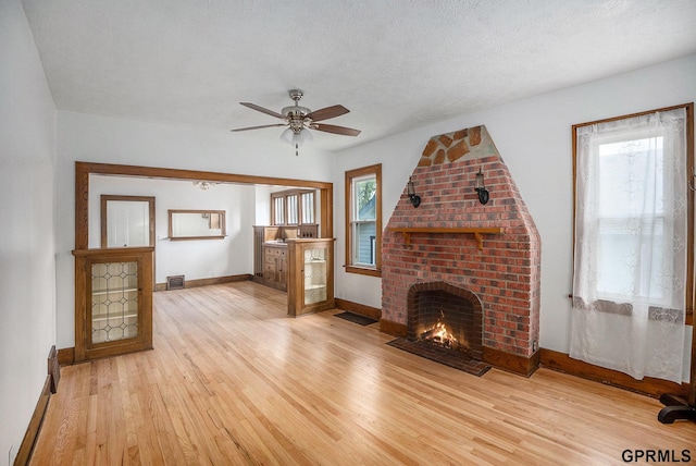 4315 N 39th St, Omaha, NE 68111 - unfurnished living room featuring baseboards, light wood finished floors, ceiling fan, a fireplace, and healthy amount of natural light