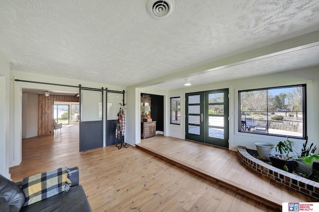 209 N Maloney Dr, North Platte, NE 69101 - living room featuring a textured ceiling, a barn door, light wood finished floors, and french doors