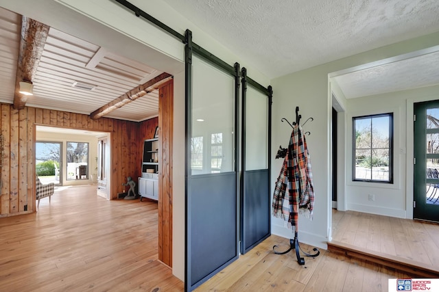 209 N Maloney Dr, North Platte, NE 69101 - foyer featuring a barn door, light wood-type flooring, wooden walls, and a textured ceiling