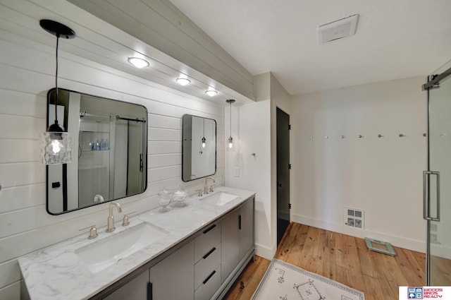 209 N Maloney Dr, North Platte, NE 69101 - bathroom with wood finished floors, double vanity, a stall shower, and baseboards