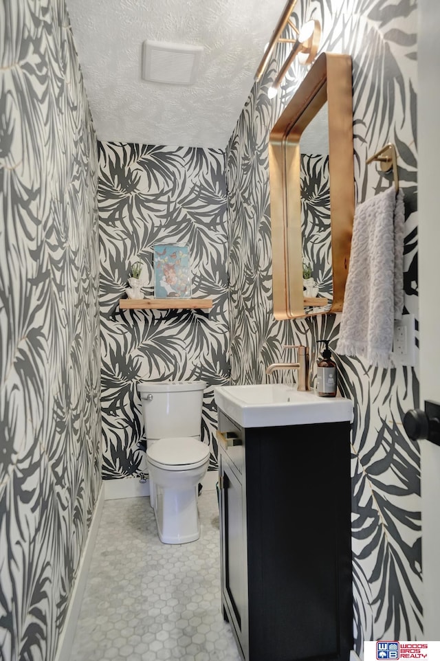 209 N Maloney Dr, North Platte, NE 69101 - bathroom with toilet, vanity, a textured ceiling, wallpapered walls, and baseboards