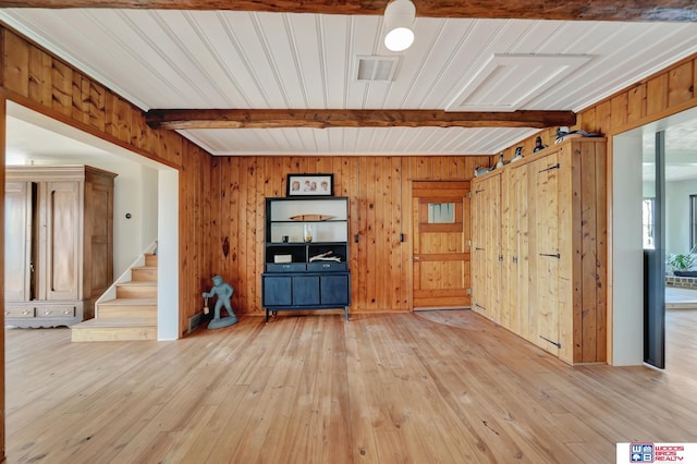 209 N Maloney Dr, North Platte, NE 69101 - unfurnished living room with beam ceiling, light wood finished floors, wood walls, and stairway