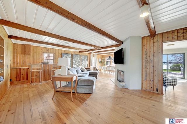 209 N Maloney Dr, North Platte, NE 69101 - living room featuring wood walls, beamed ceiling, light wood-type flooring, healthy amount of natural light, and a glass covered fireplace