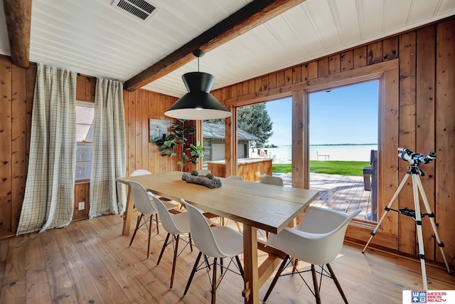 209 N Maloney Dr, North Platte, NE 69101 - dining space with a water view, wooden walls, plenty of natural light, beam ceiling, and light wood-style floors