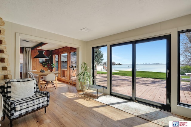 209 N Maloney Dr, North Platte, NE 69101 - sunroom with wood-type flooring, a deck with water view, wooden walls, and a textured ceiling
