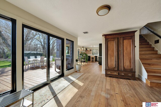 209 N Maloney Dr, North Platte, NE 69101 - doorway to outside with light wood-type flooring, healthy amount of natural light, stairway, a chandelier, and a textured ceiling
