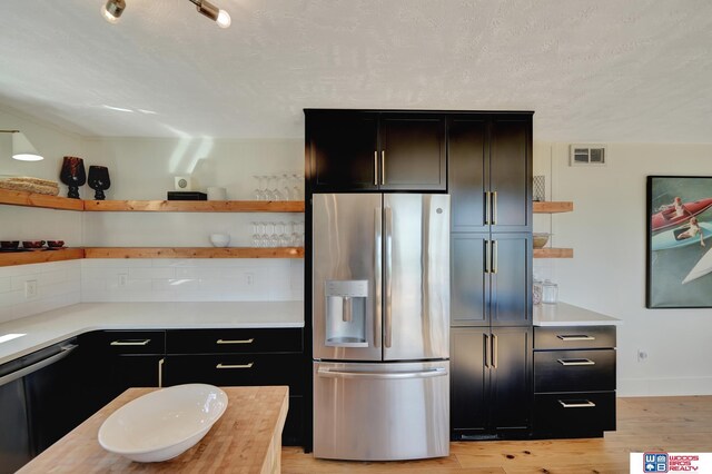 209 N Maloney Dr, North Platte, NE 69101 - kitchen with open shelves, stainless steel fridge, light countertops, backsplash, and light wood-style floors