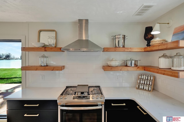 209 N Maloney Dr, North Platte, NE 69101 - kitchen featuring open shelves, wall chimney exhaust hood, stainless steel gas range, and dark cabinetry