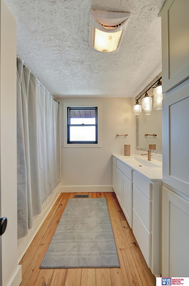 209 N Maloney Dr, North Platte, NE 69101 - full bath with vanity, wood finished floors, a textured ceiling, a shower with shower curtain, and baseboards