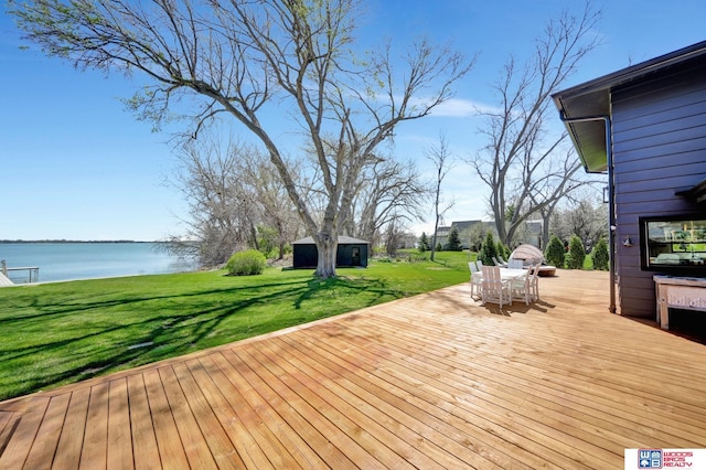 209 N Maloney Dr, North Platte, NE 69101 - wooden deck with a water view, an outbuilding, a yard, and outdoor dining area