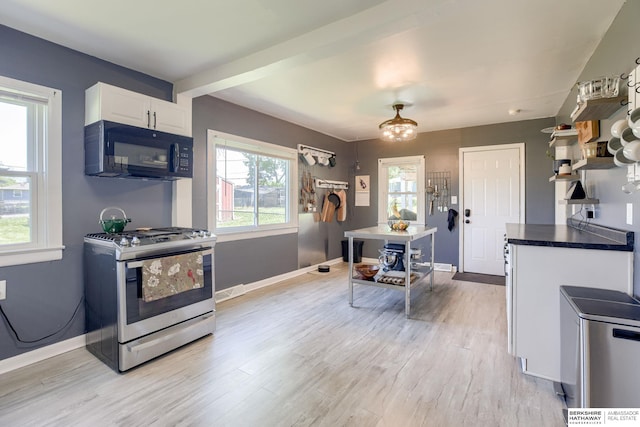 4332 Vinton St, Omaha, NE 68105 - kitchen featuring black microwave, stainless steel gas range oven, light wood-style flooring, and white cabinets
