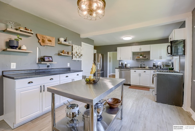4332 Vinton St, Omaha, NE 68105 - kitchen featuring open shelves, stainless steel appliances, dark countertops, a sink, and white cabinetry