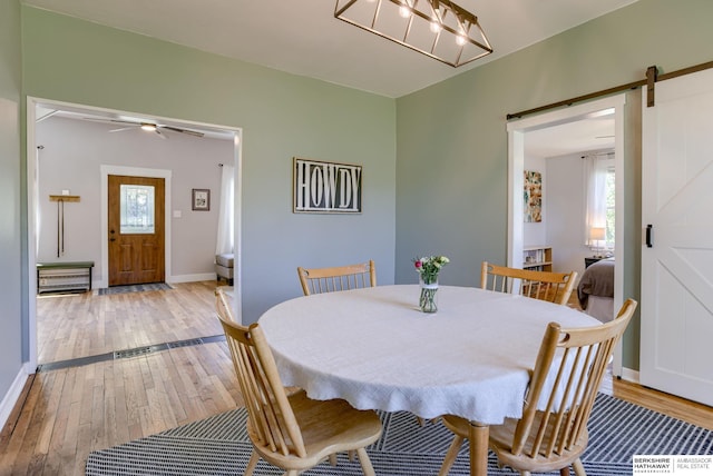 4332 Vinton St, Omaha, NE 68105 - dining space featuring a barn door, healthy amount of natural light, light wood-style flooring, and baseboards