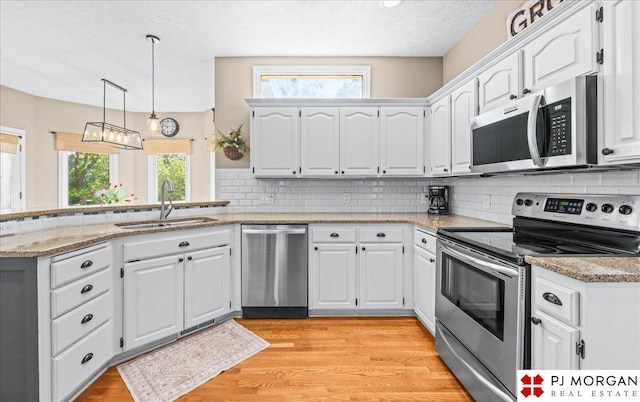 5517 S 174th Ave, Omaha, NE 68135 - kitchen featuring stainless steel appliances, a sink, a peninsula, light wood-style flooring, and light stone countertops