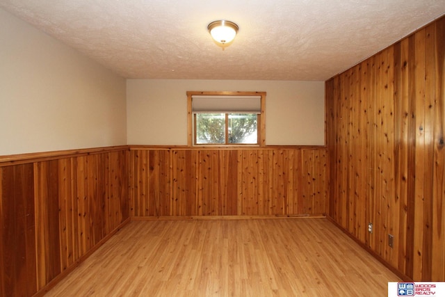 1912 SW 25th St, Lincoln, NE 68522 - spare room featuring a textured ceiling, light wood-type flooring, wooden walls, and wainscoting