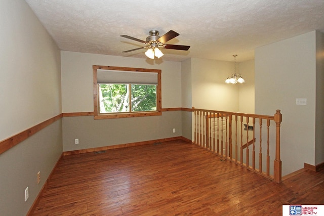 1912 SW 25th St, Lincoln, NE 68522 - spare room featuring wood finished floors, a ceiling fan, a chandelier, baseboards, and a textured ceiling