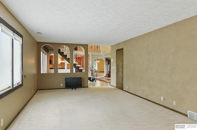 2564 County Road 12, Fremont, NE 68025 - unfurnished living room with arched walkways, stairs, carpet, a textured ceiling, and baseboards