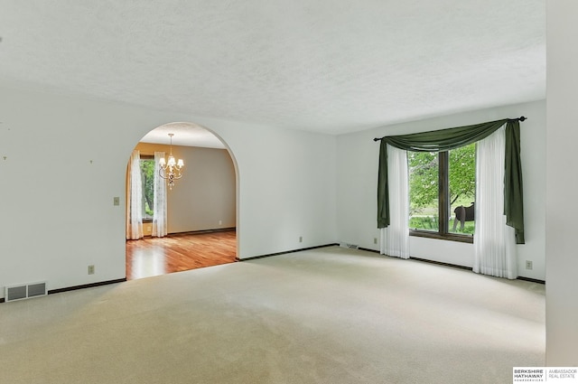 2564 County Road 12, Fremont, NE 68025 - spare room featuring carpet, arched walkways, a chandelier, baseboards, and a textured ceiling