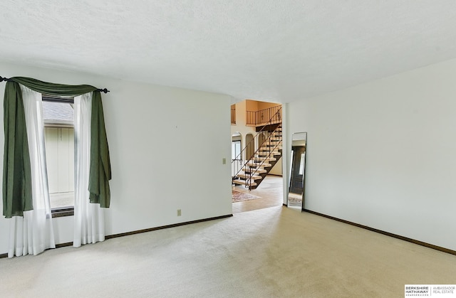2564 County Road 12, Fremont, NE 68025 - unfurnished room featuring plenty of natural light, light carpet, baseboards, stairway, and a textured ceiling