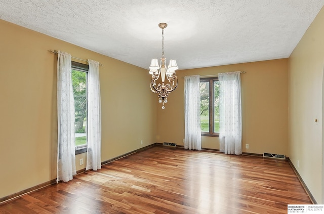 2564 County Road 12, Fremont, NE 68025 - spare room featuring healthy amount of natural light, a chandelier, wood finished floors, a textured ceiling, and baseboards