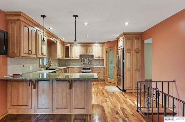 2564 County Road 12, Fremont, NE 68025 - kitchen with appliances with stainless steel finishes, a sink, a peninsula, light wood-style flooring, and dark stone counters