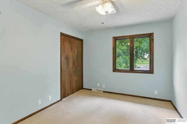 2564 County Road 12, Fremont, NE 68025 - unfurnished bedroom featuring a textured ceiling, a closet, carpet flooring, baseboards, and ceiling fan