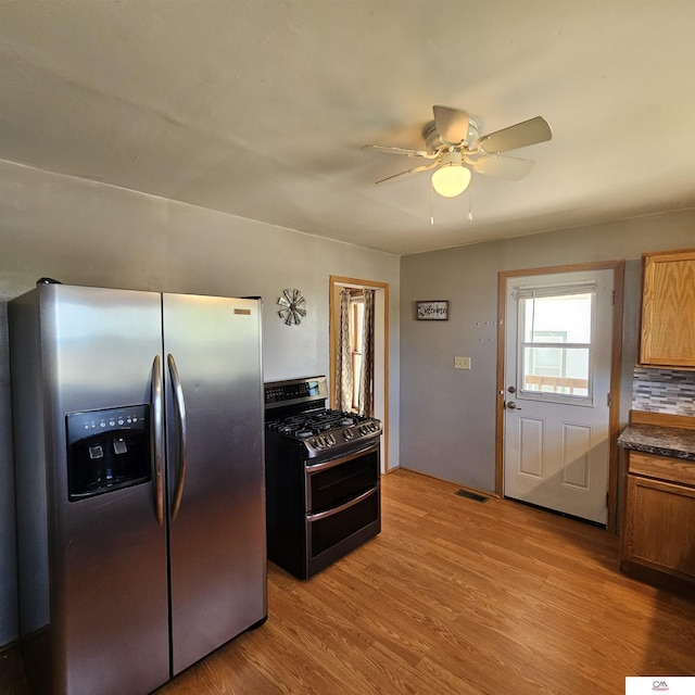 1119 H St, Fairbury, NE 68352 - kitchen with appliances with stainless steel finishes, a ceiling fan, light wood-type flooring, dark countertops, and brown cabinets
