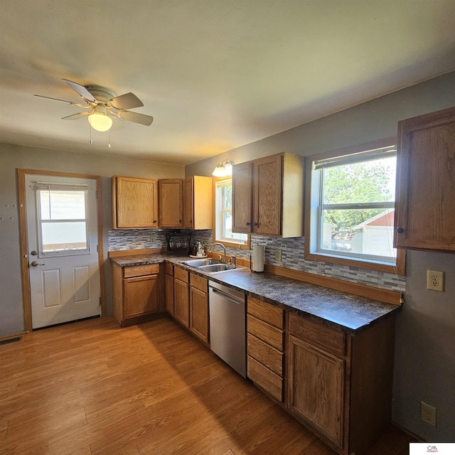 1119 H St, Fairbury, NE 68352 - kitchen with stainless steel dishwasher, a sink, decorative backsplash, dark countertops, and light wood-type flooring