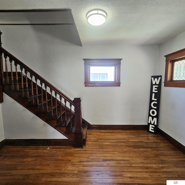 1119 H St, Fairbury, NE 68352 - foyer with plenty of natural light, stairway, wood finished floors, and a textured ceiling