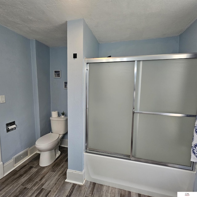 1119 H St, Fairbury, NE 68352 - full bath featuring toilet, wood finished floors, baseboards, bath / shower combo with glass door, and a textured ceiling
