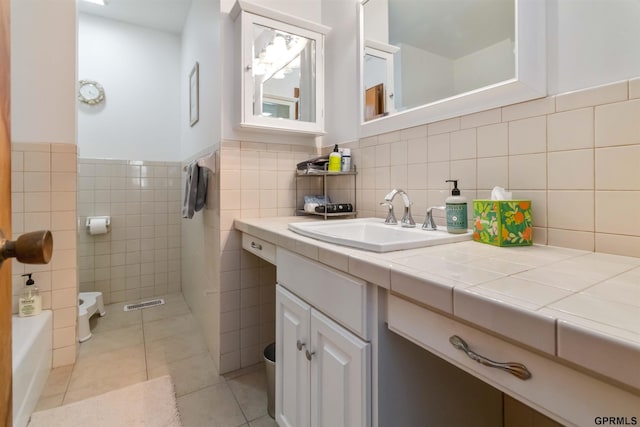 2206 N 56th St, Omaha, NE 68104 - bathroom featuring tile patterned flooring, vanity, toilet, tile walls, and a tub to relax in