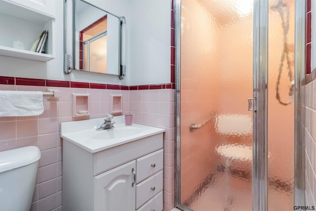2206 N 56th St, Omaha, NE 68104 - bathroom featuring toilet, tile walls, vanity, a stall shower, and a wainscoted wall