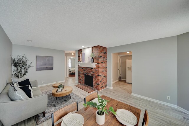 1625 Granada Ln, Lincoln, NE 68528 - living area with light wood-style floors, a textured ceiling, baseboards, and a brick fireplace