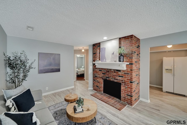 1625 Granada Ln, Lincoln, NE 68528 - living room featuring light wood-style flooring, a textured ceiling, a brick fireplace, and baseboards