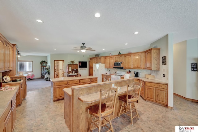 40798 US Highway 6, Cambridge, NE 69022 - kitchen with white appliances, a kitchen island, a ceiling fan, recessed lighting, and baseboards