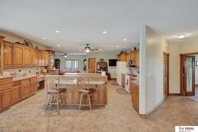 40798 US Highway 6, Cambridge, NE 69022 - kitchen featuring white appliances, a center island with sink, a kitchen bar, recessed lighting, and light countertops