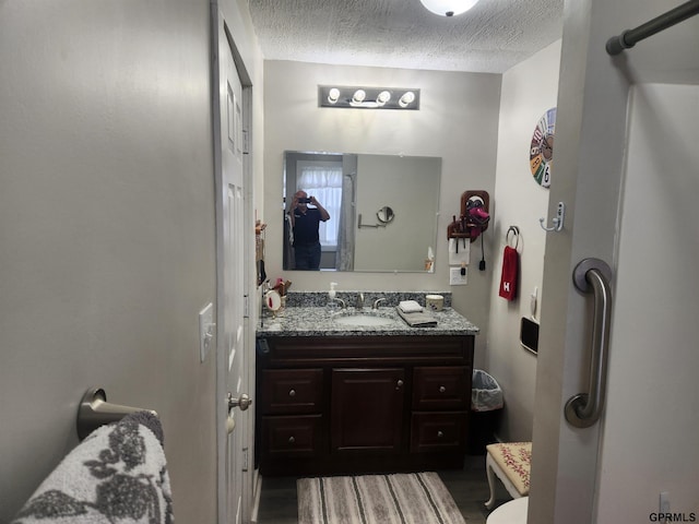 1211 D St, Fairbury, NE 68352 - bathroom with vanity, wood finished floors, and a textured ceiling