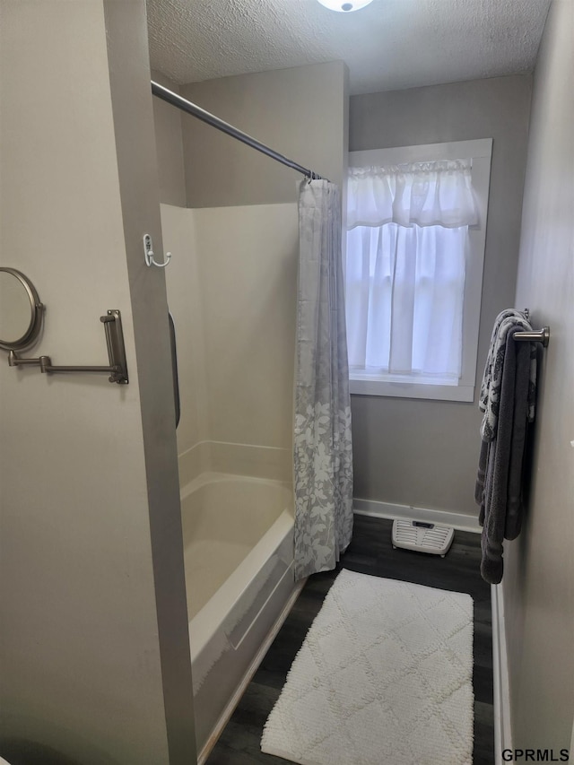 1211 D St, Fairbury, NE 68352 - full bathroom featuring baseboards, shower / bath combo with shower curtain, wood finished floors, and a textured ceiling