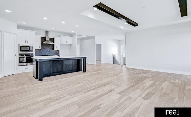 12003 S 109th St, Papillion, NE 68046 - kitchen with appliances with stainless steel finishes, wall chimney range hood, a kitchen island with sink, white cabinets, and light wood finished floors